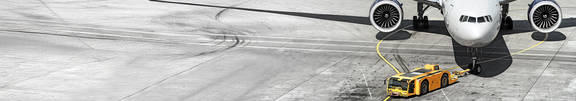 Aircraft tug fitted with durable airport tires towing a passenger airplane on the tarmac.