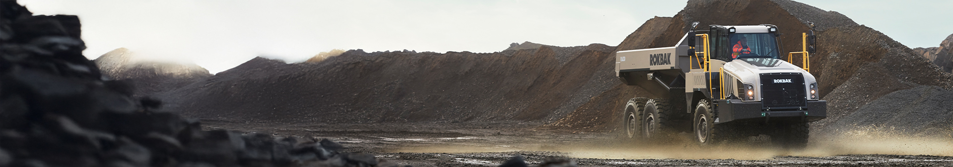 Rokbak RA30 articulated dump truck fitted with rugged mining tyres driving through a dusty mining site.