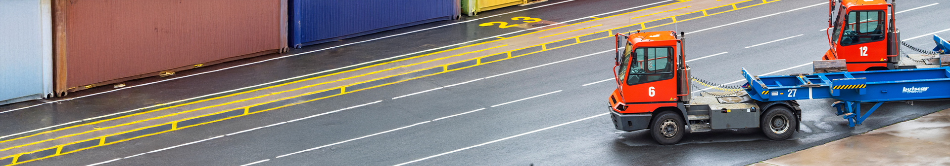 Terminal tractors equipped with durable terminal tires transporting containers at a port logistics area.