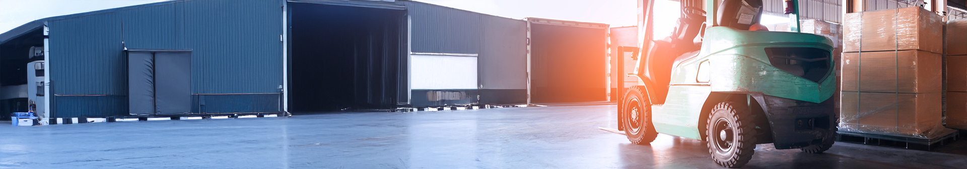 Forklift equipped with durable warehouse tires transporting pallets inside a loading dock area.